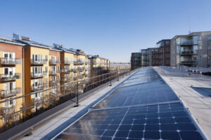 Ett tak täckt med solpaneler i ett skandinaviskt bostadsområde, vilket visar hållbar energi och minskade elkostnader. Inga människor syns.
