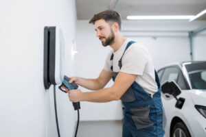 Elektriker installerar en laddbox i ett garage, fokus på installationen.
