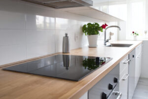 Ett modernt kök med induktionshäll där en elektriker utför en korrekt installation, vilket framhäver vikten av behörighet.