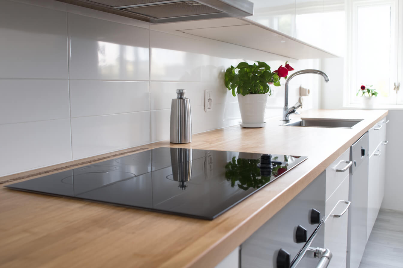 Ett modernt kök med induktionshäll där en elektriker utför en korrekt installation, vilket framhäver vikten av behörighet.
